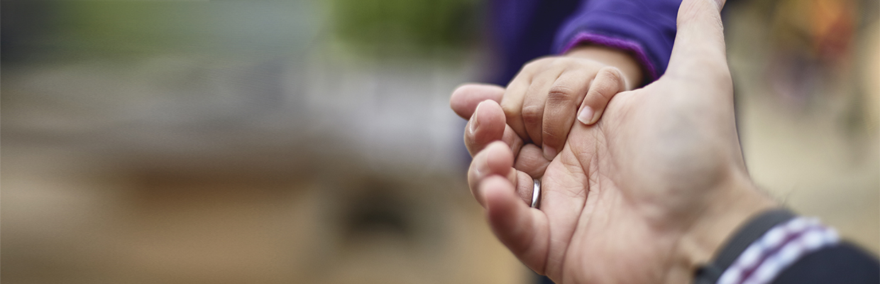 A child is holding his father's hand; image used in help and support page