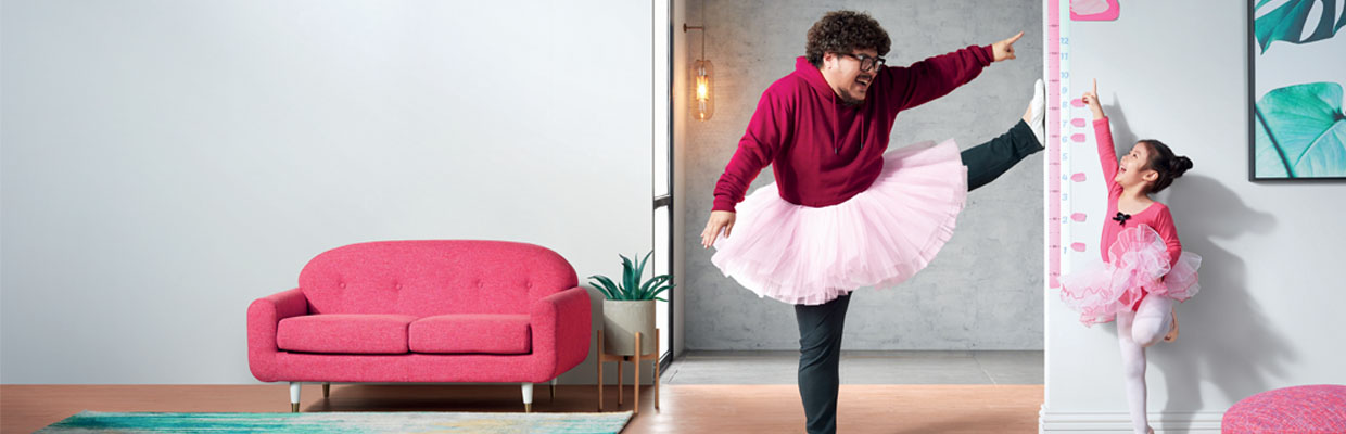 Dad and his daughter are dressing up in ballet costumes and measuring their heights at home; image used for HSBC Life Insurance products TargetSave.