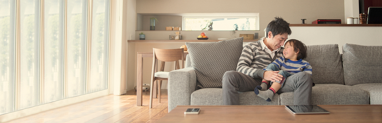 A father is holding his child in sofa; image used for HSBC Term Life Insurance.