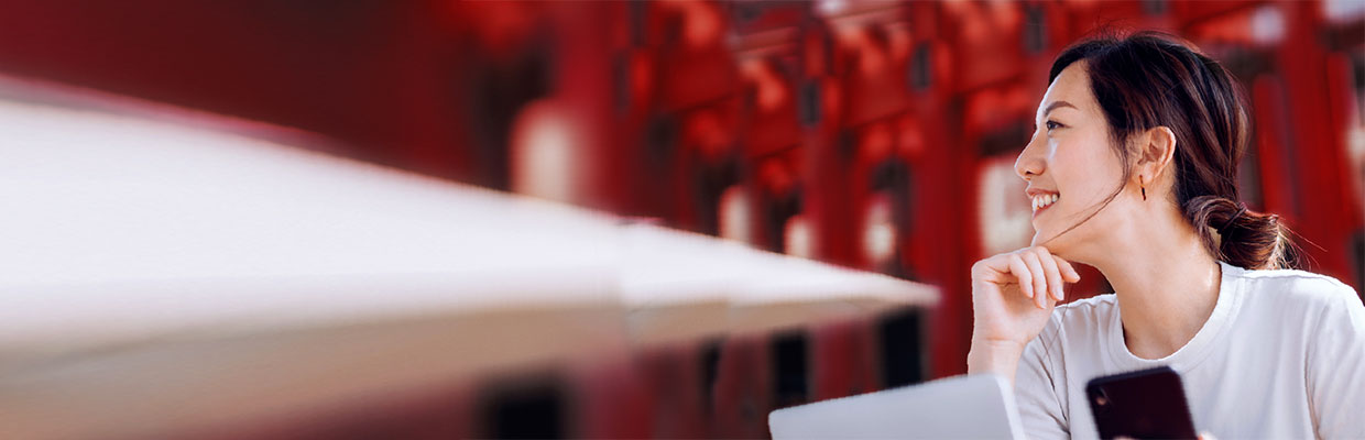 A woman is leaning on a sofa and using a smart phone ; image used in HSBC Broking page